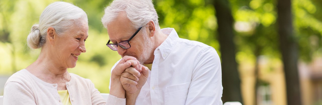 An older couple sitting together on a park bench